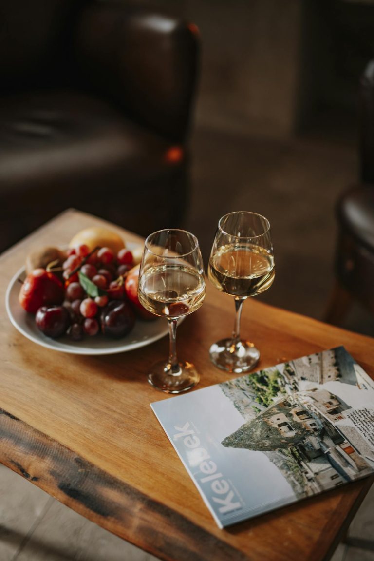 A wooden table with two glasses of wine and a magazine